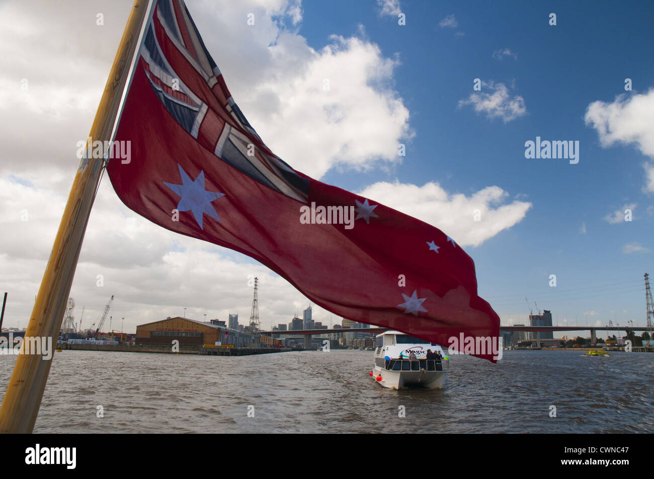 Australia's Red Ensign flutters at the stern of a vessel which has passed out under the Bolte Bridge in the Melbourne Docklands Stock Photo