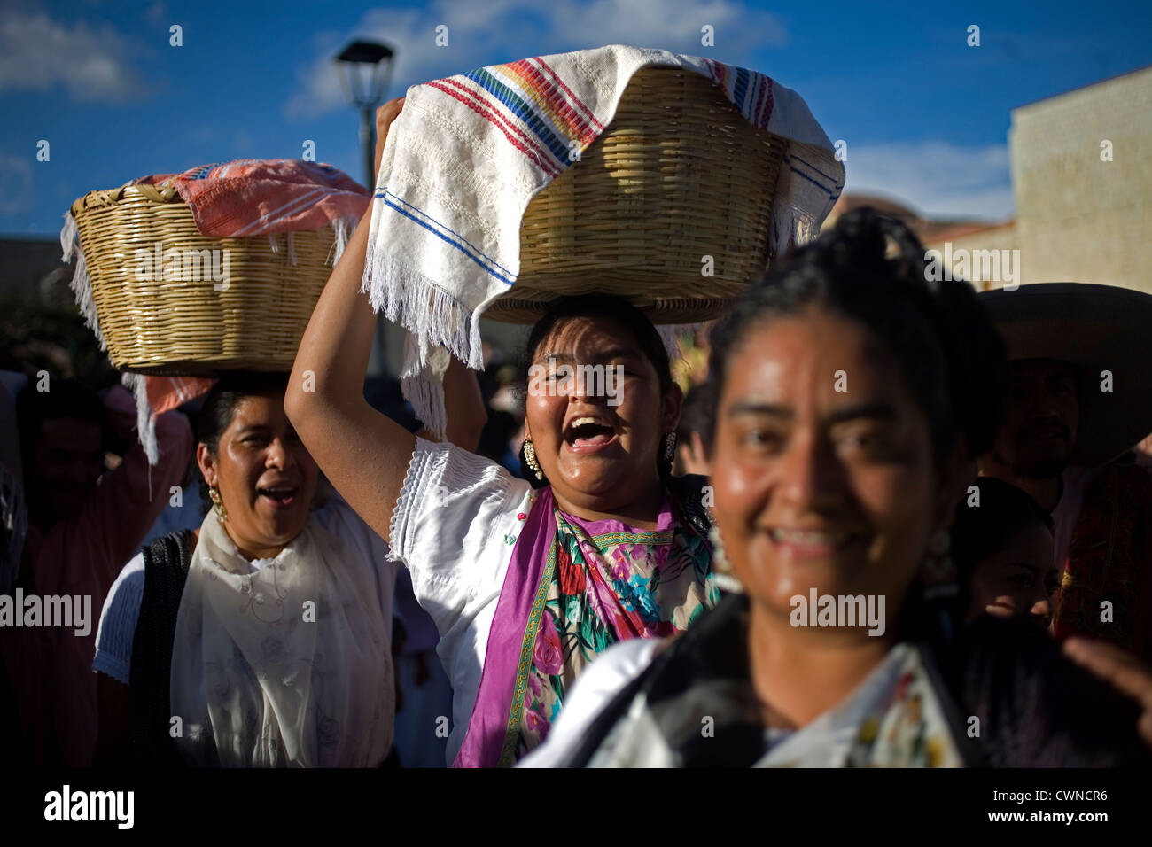 Women smile and carry baskets with food in their heads during the