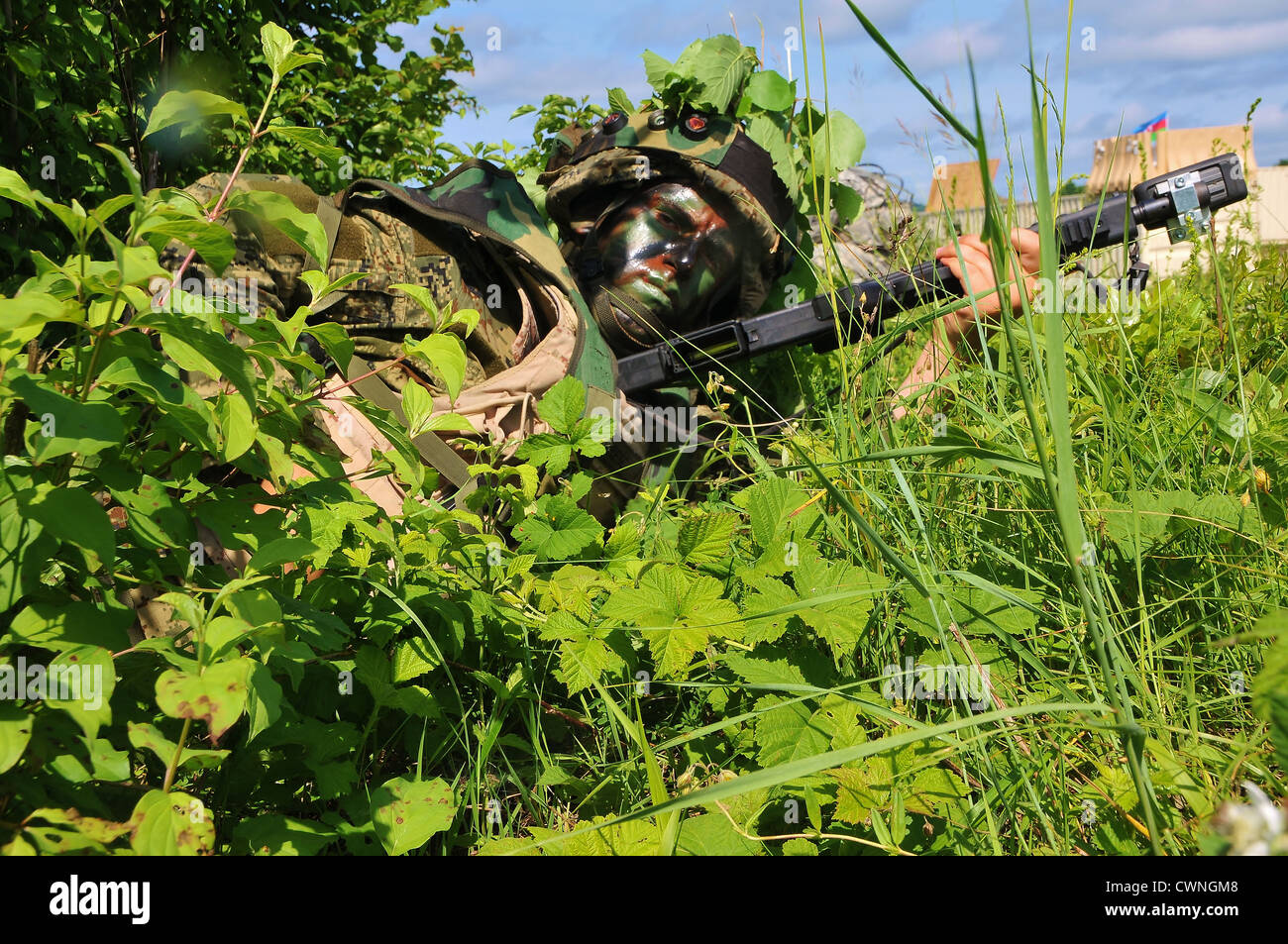 A Croatian Ground Forces soldier with painted black face changes his magazine during a field training exercise as part of Immediate Response 2012, a US Army/Europe-led joint field training exercise June 6, 2012 in Slunj, Croatia. Stock Photo