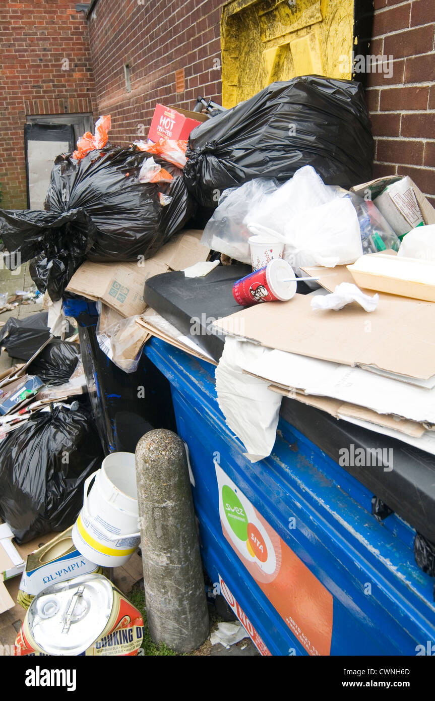 overflowing bin bins full dumpster dumpster in back alley alleyway trash rubbish can cans collection service Stock Photo