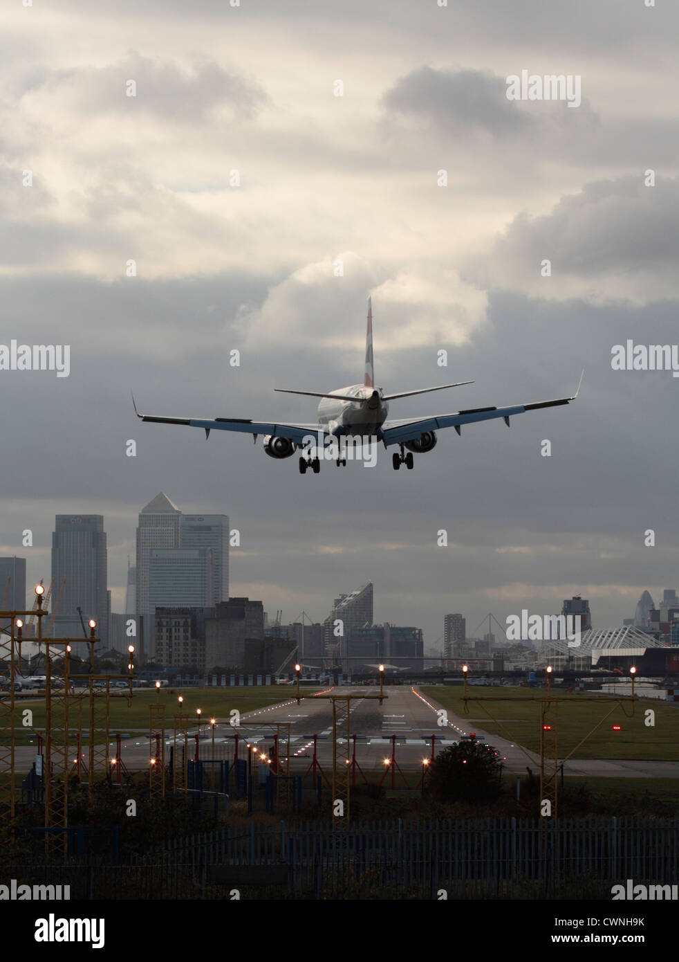 Air travel in the UK. Jet plane landing at London City Airport, with the runway in sight and the financial district visible in the background. Stock Photo