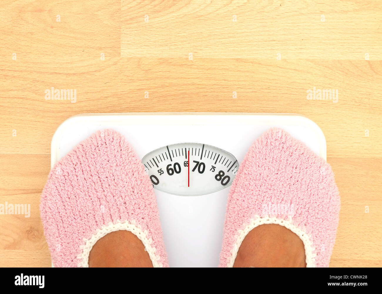 https://c8.alamy.com/comp/CWNK28/woman-in-woolly-pink-slippers-on-bathroom-scales-weight-watching-CWNK28.jpg