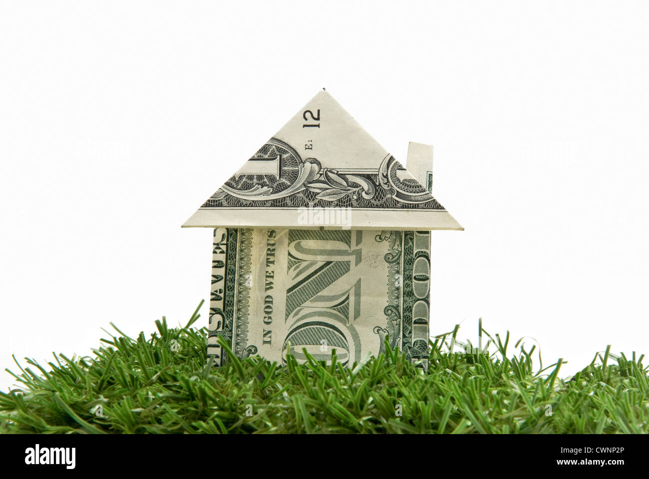 House folded from a dollar bill on artificial turf, white background Stock Photo