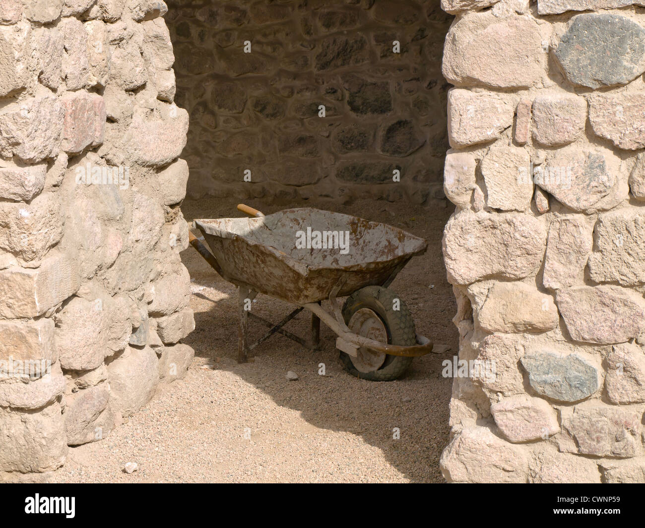 Wheelbarrow in the shadow of stone walls in an archaeological site in Aqaba  Jordan Stock Photo