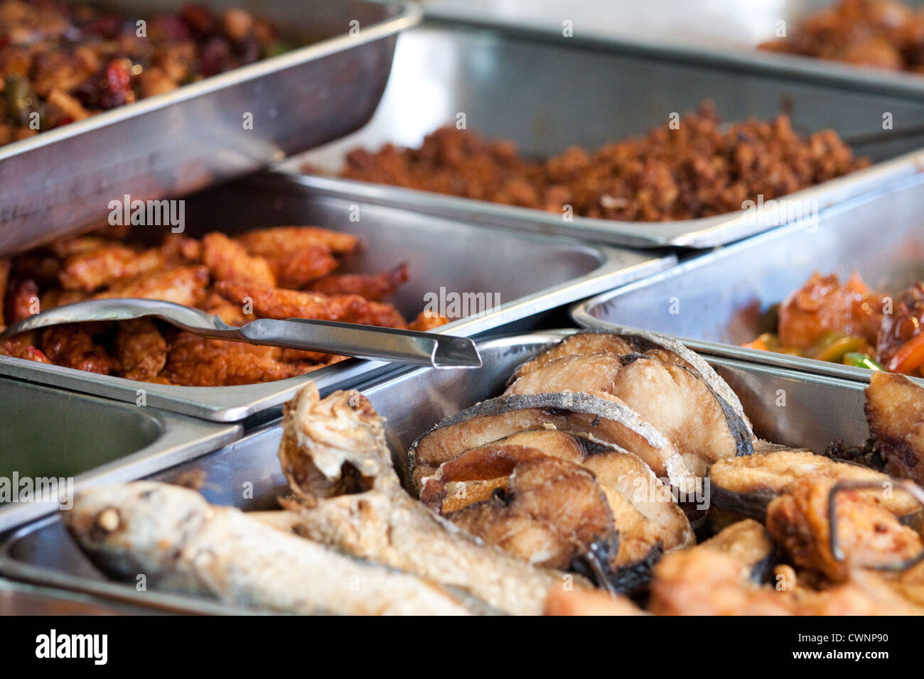 Aluminium containers with fried fish and other tasty Malaysian street food at a food stall in the city of Kuala Lumpur. Self service buffet style Stock Photo