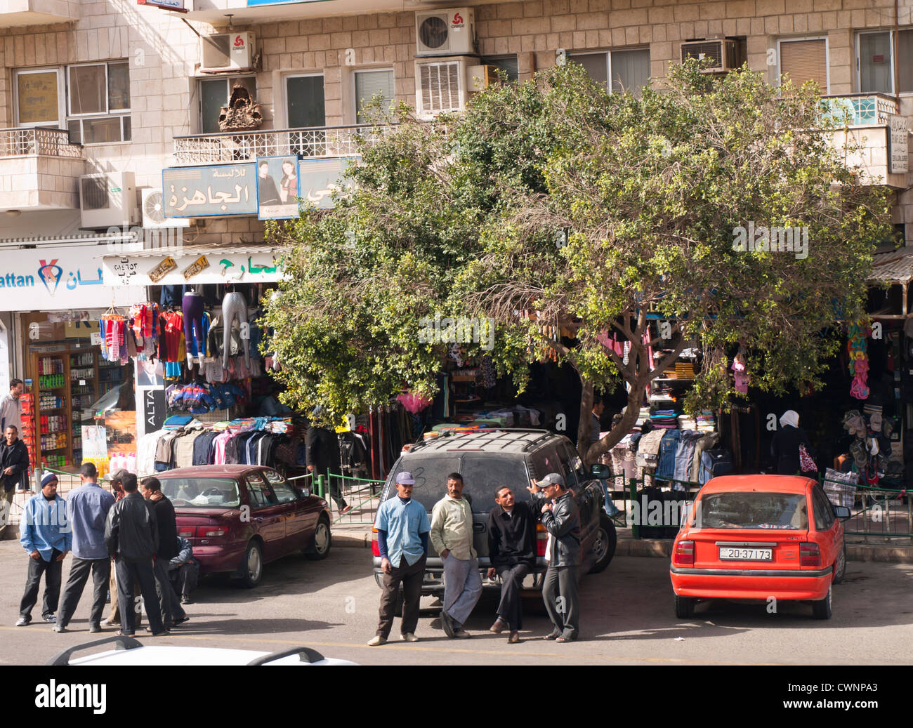 Everyday life in a shopping street in Aqaba Jordan with shop fronts goods on display , of med discussing and cars Stock Photo Alamy