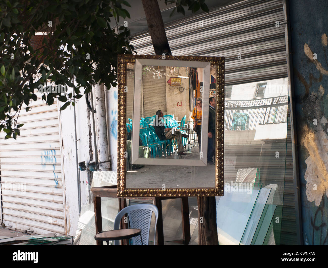 Mirror with extra frame hanging outside a shop in Aqaba Jordan, showing the image of a man enjoying his narghile waterpipe Stock Photo