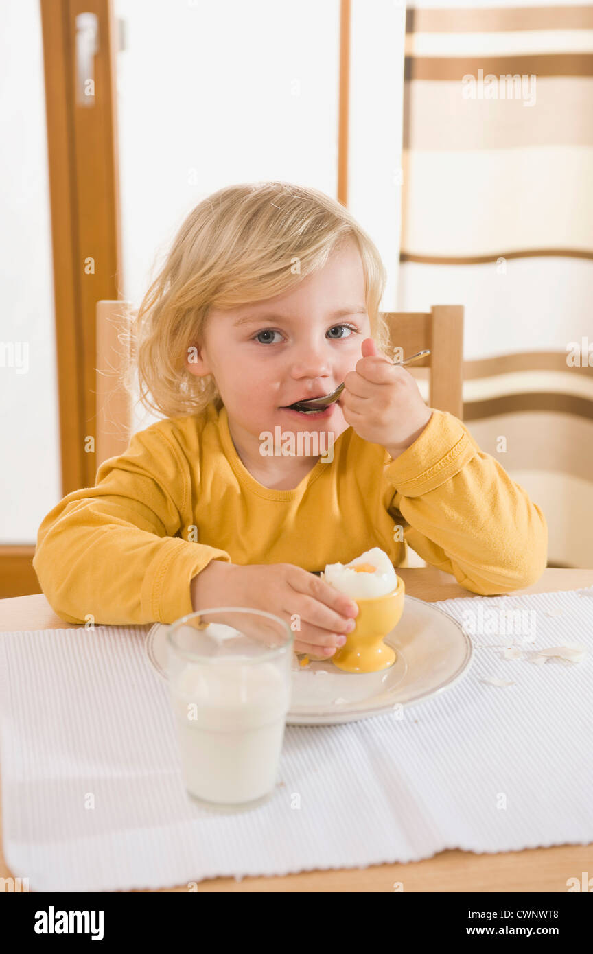 Girl eating boiled egg in breakfast hires stock photography and images
