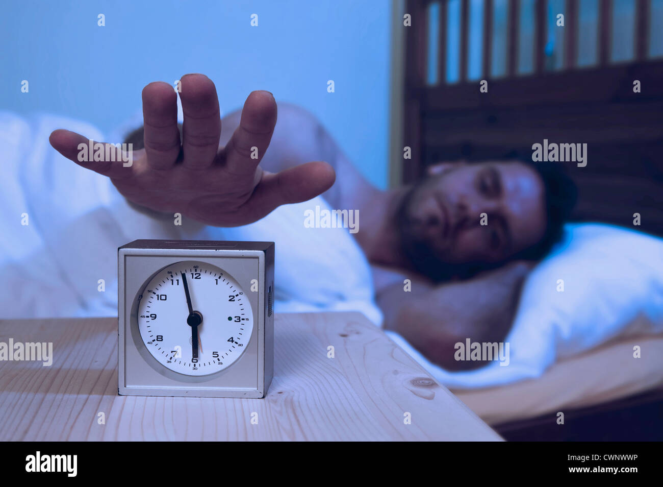 Man turning off alarm clock Stock Photo Alamy