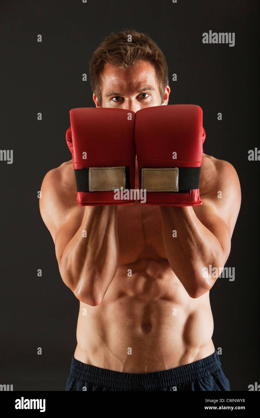 Barechested boxer holding up gloves in front of face in defensive position Stock Photo