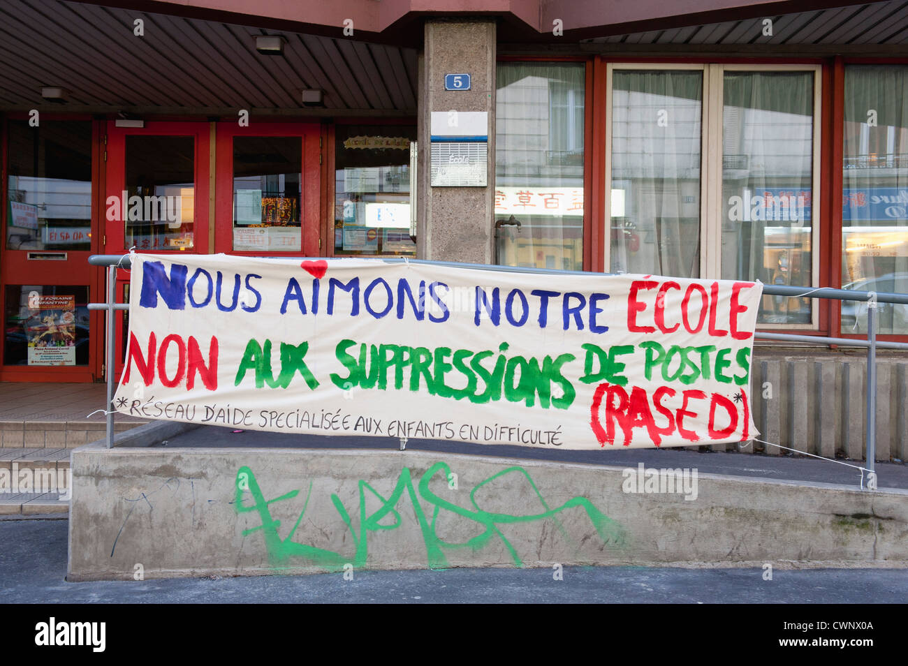Banner lprotesting educational job cuts in front of school Stock Photo
