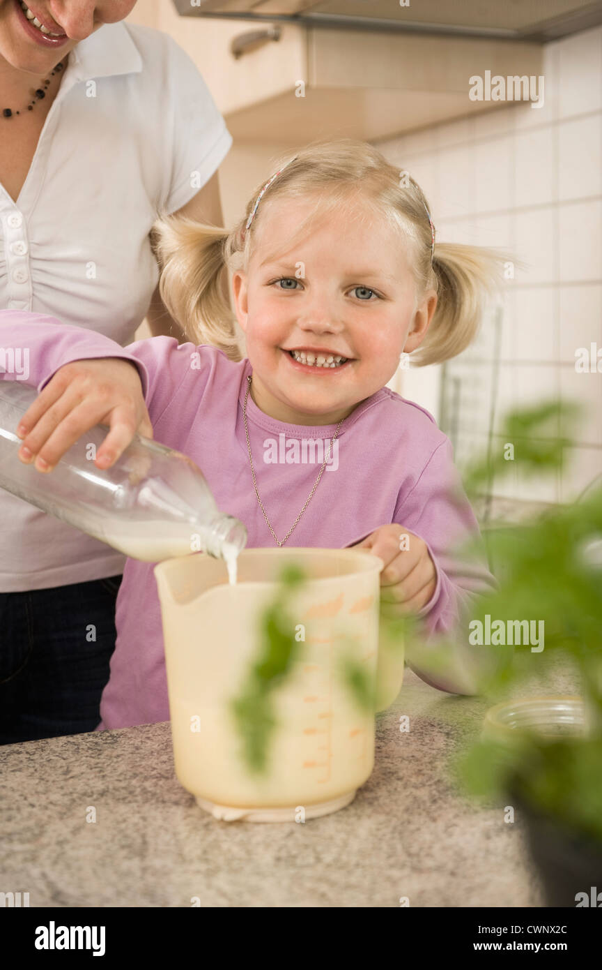 Mother and daughter pouring milk into measuring cup Stock Photo Alamy