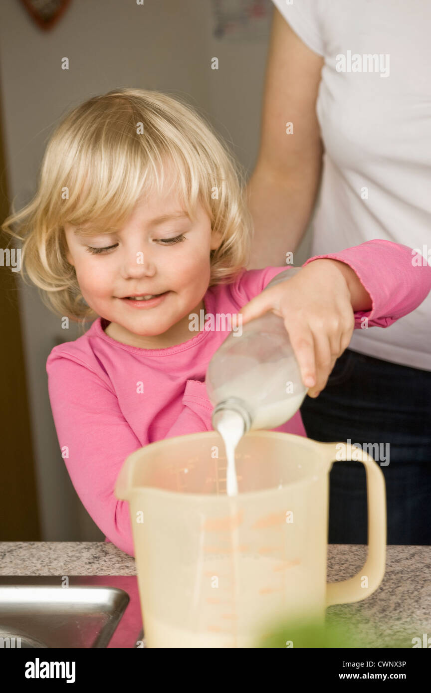 Mother and daughter pouring milk into measuring cup Stock Photo Alamy
