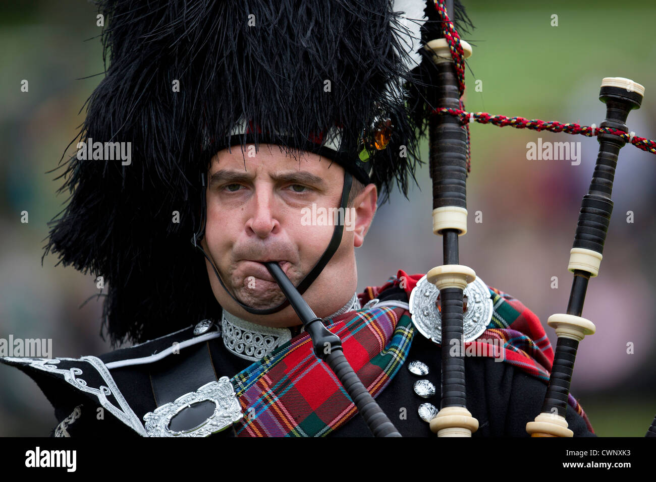 A pipe major of a pipe band blows hard into his bagpipes during the Braemar Gathering before the start of the games Stock Photo