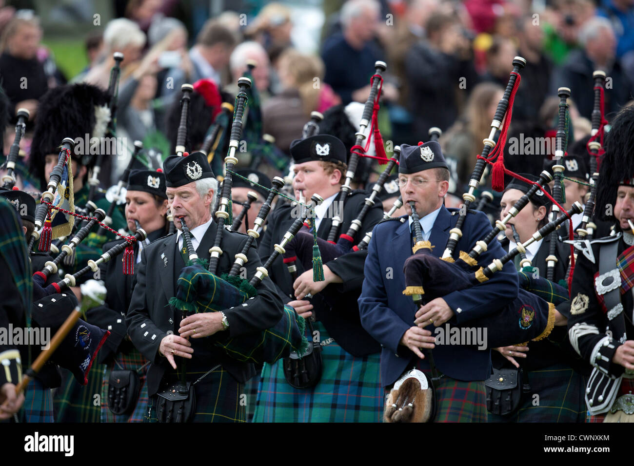 The massed pipe band parade around the sports field at the Braemar Gathering during the Highland Games. Stock Photo