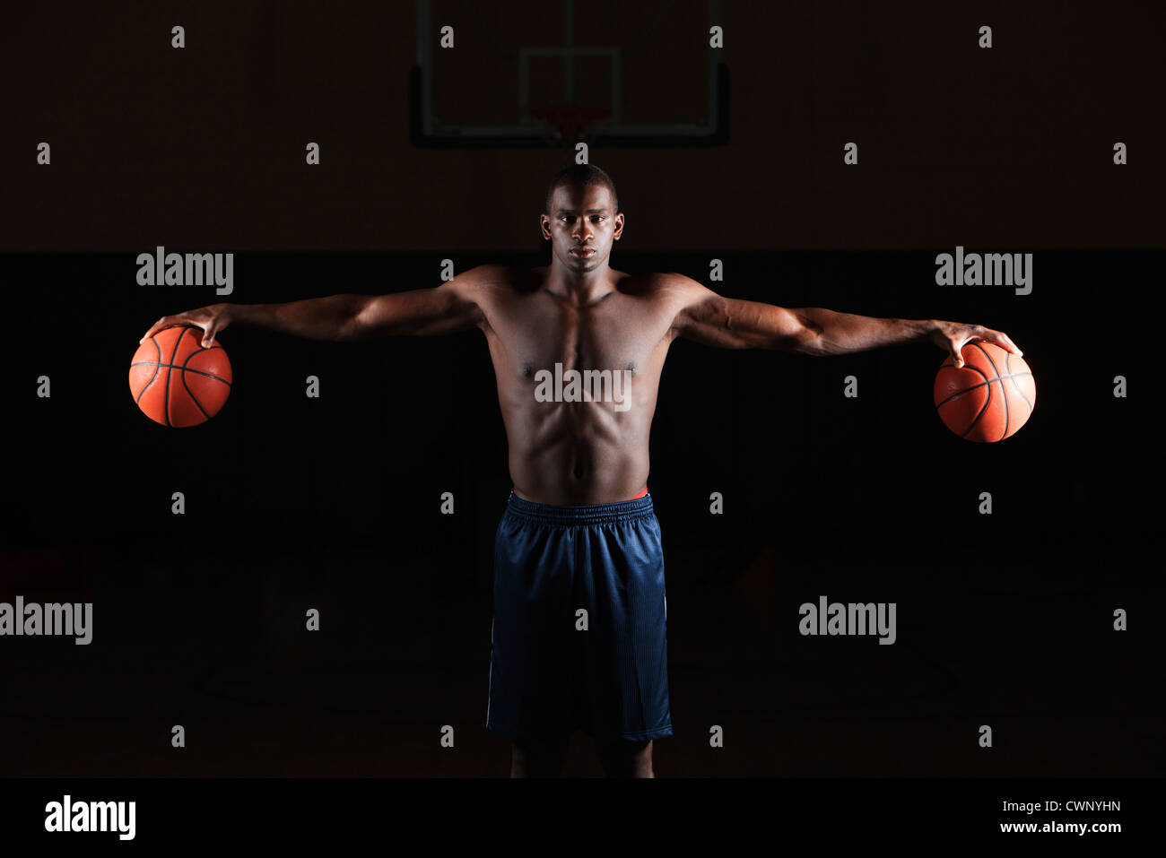 Barechested basketball player holding basketballs in both hands Stock Photo