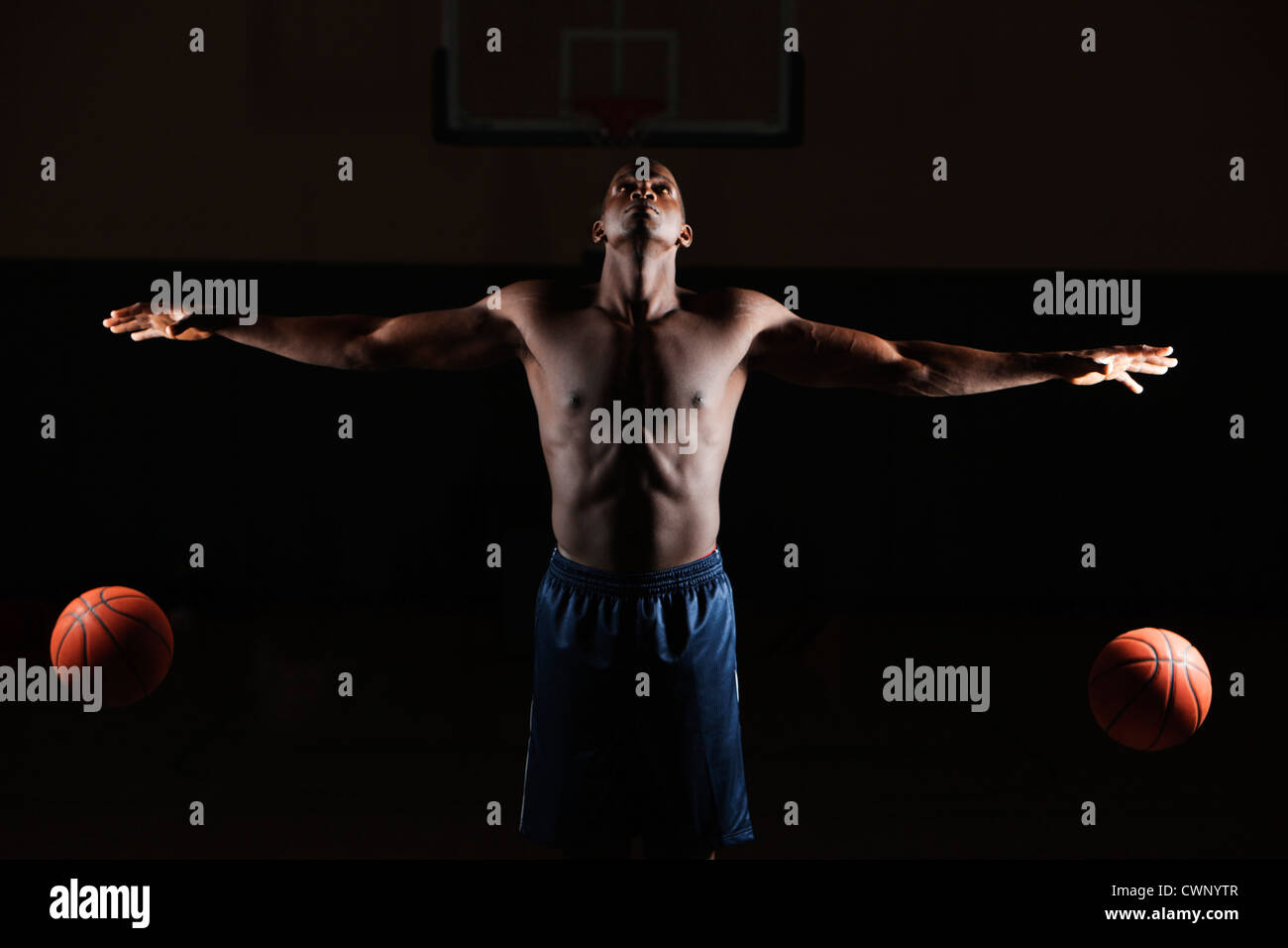 Barechested basketball player dribbling two basketballs Stock Photo