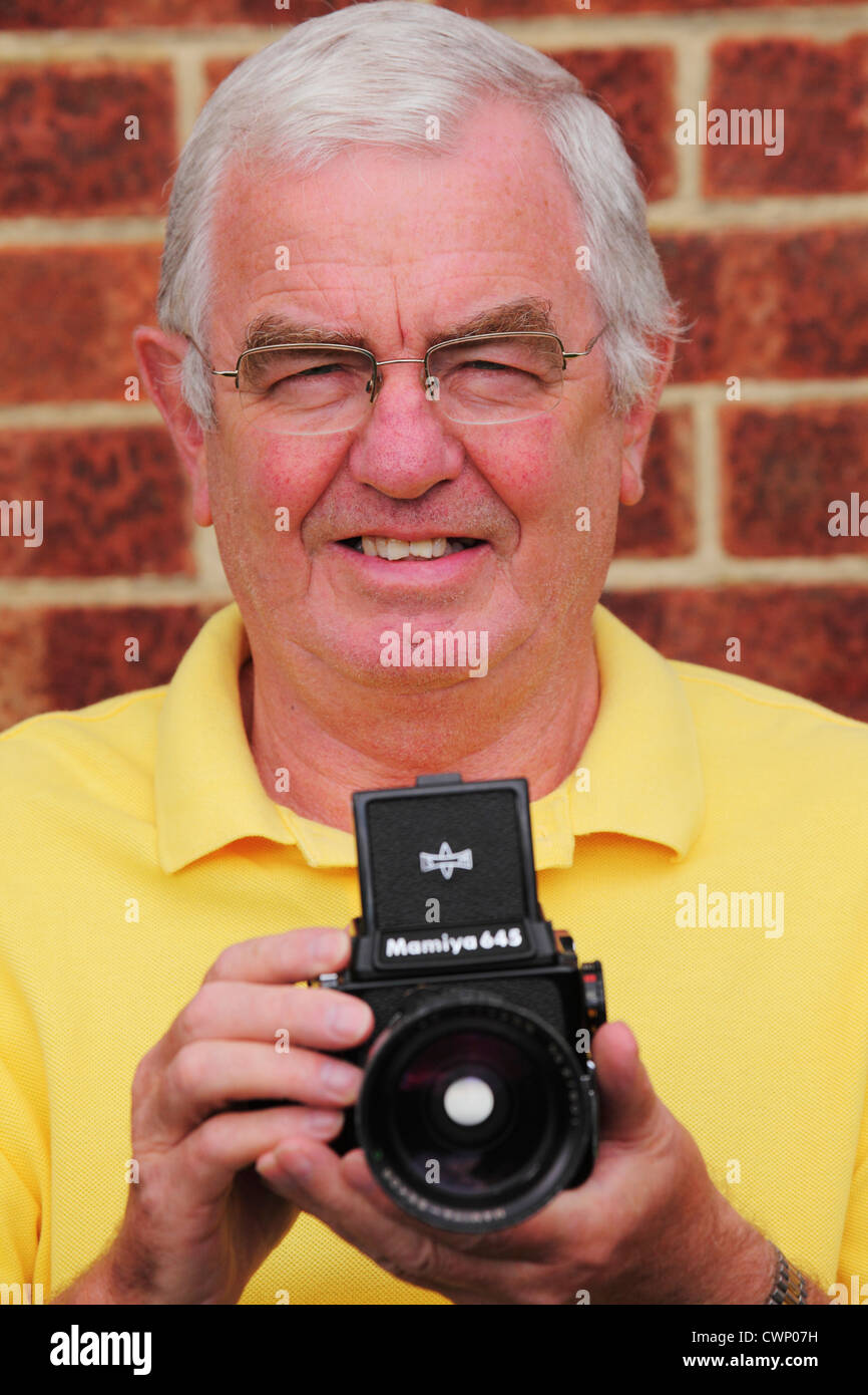 A man holds a Mamiya 645 medium format film camera. Stock Photo
