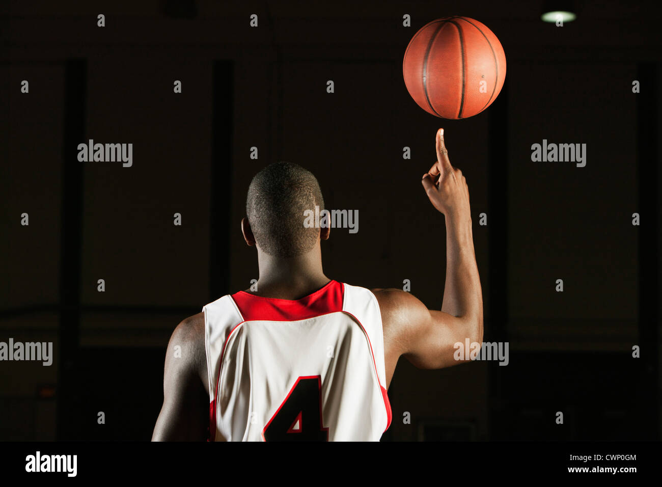 Basketball player spinning basketball atop finger, rear view Stock Photo