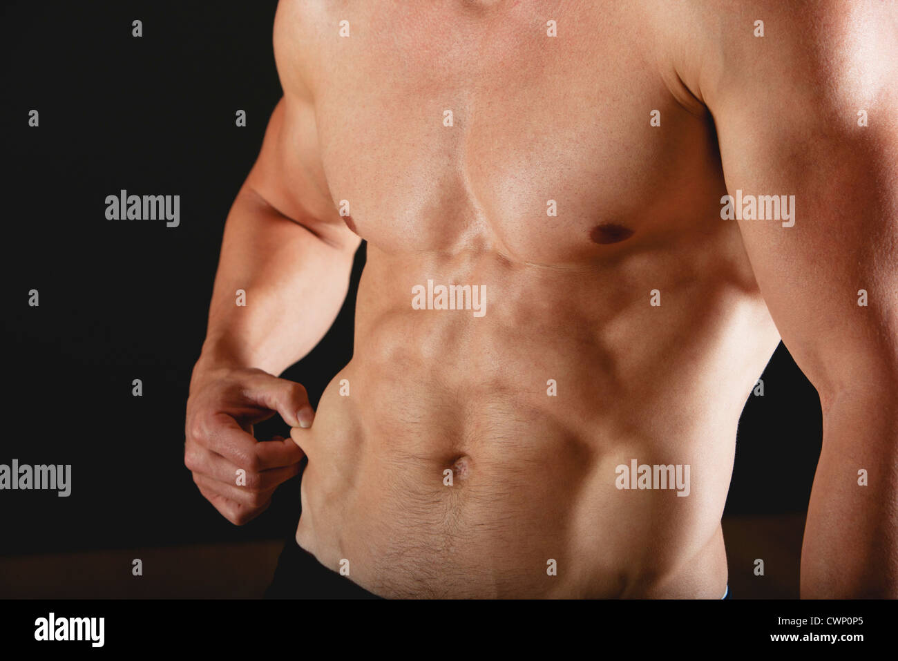 Barechested muscular man pinching waist, mid section Stock Photo