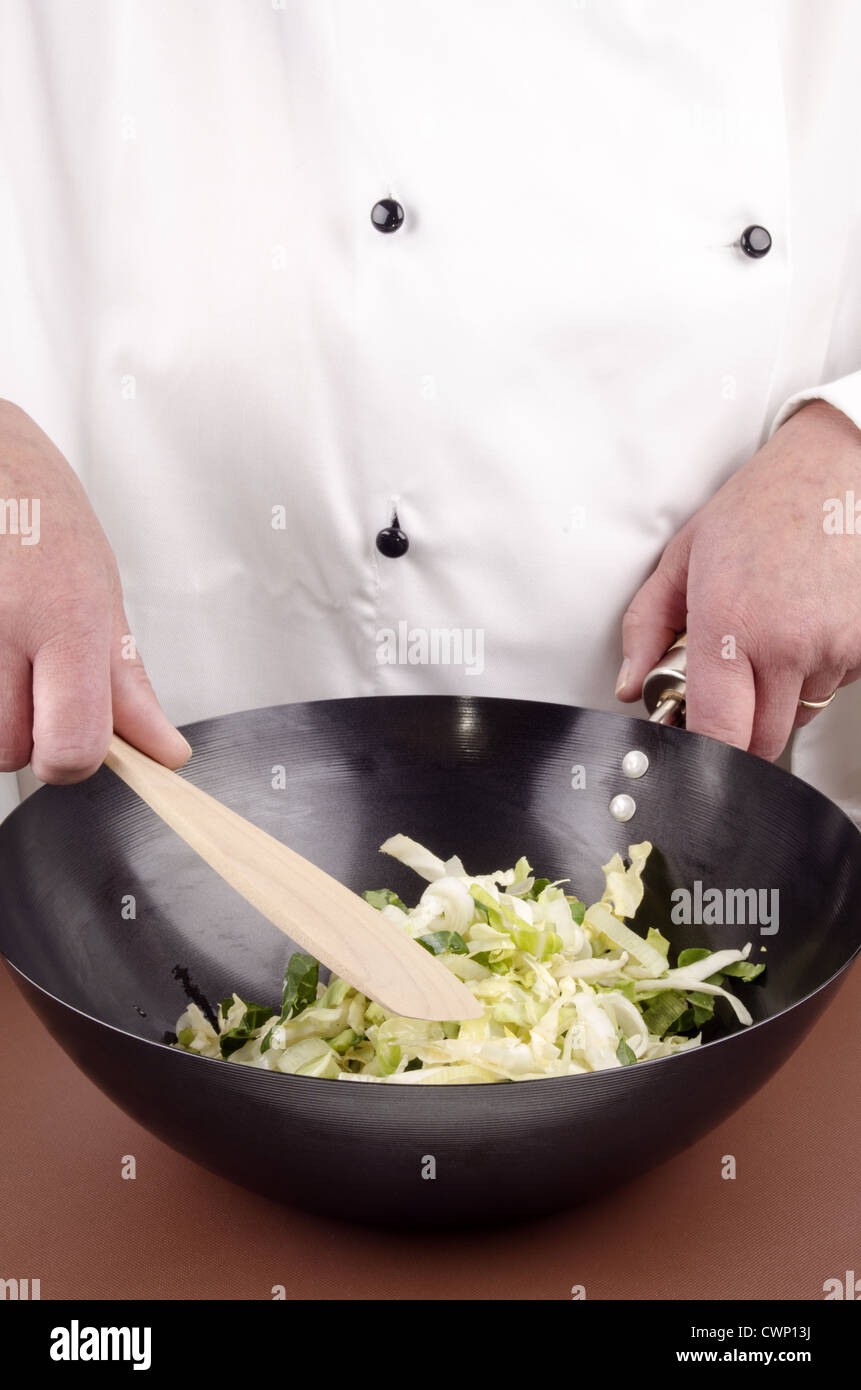 female chef and organic cabbage in a wok Stock Photo