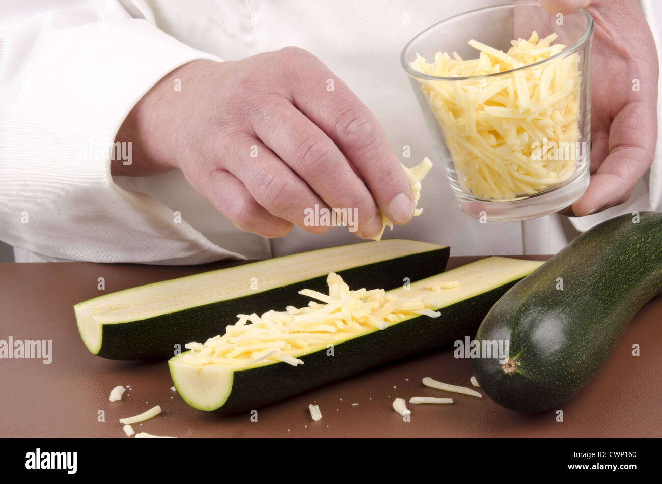 female chef and zucchini with grated cheese in her hand Stock Photo