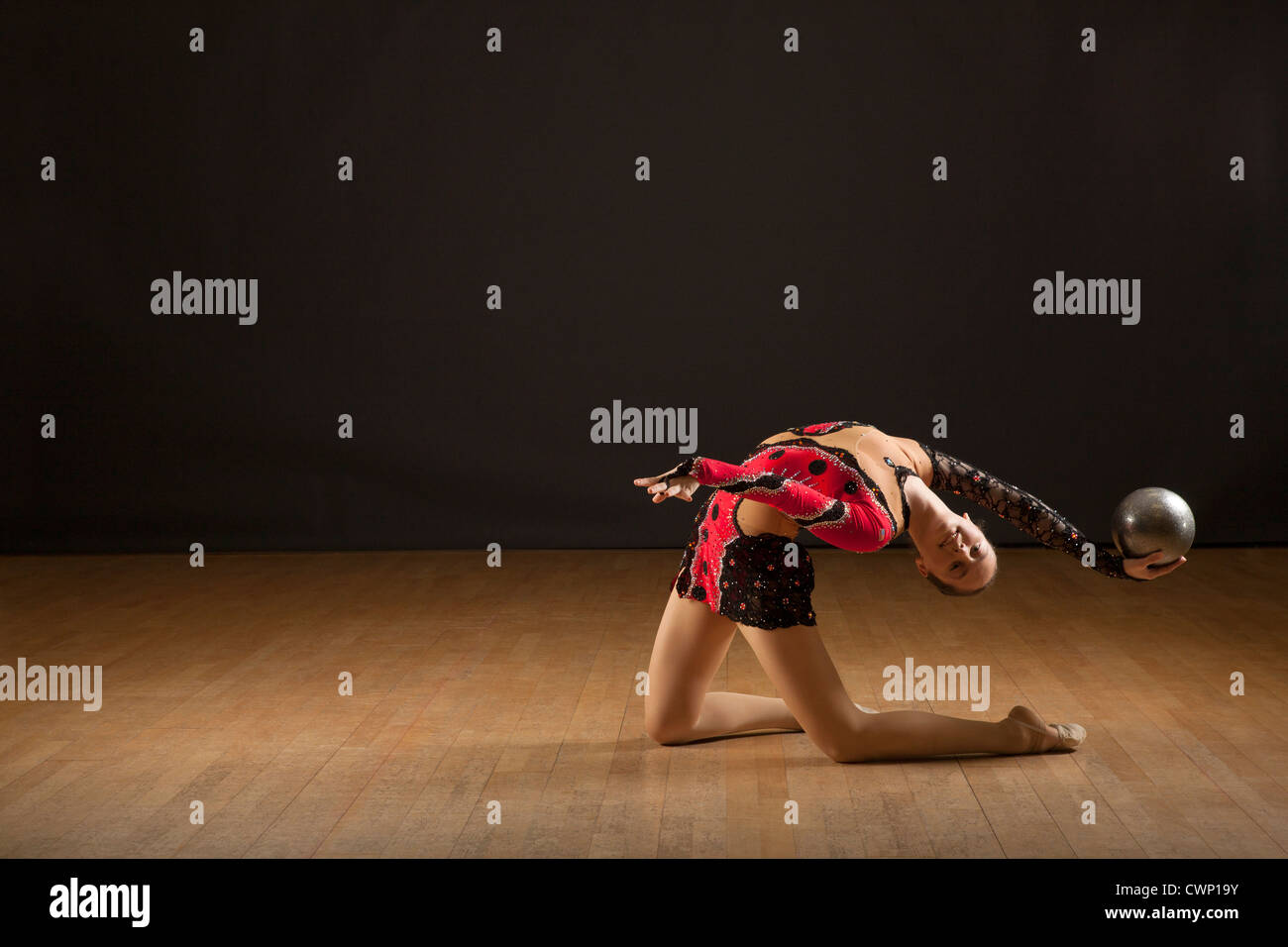 Gymnast bending backwards holding ball Stock Photo