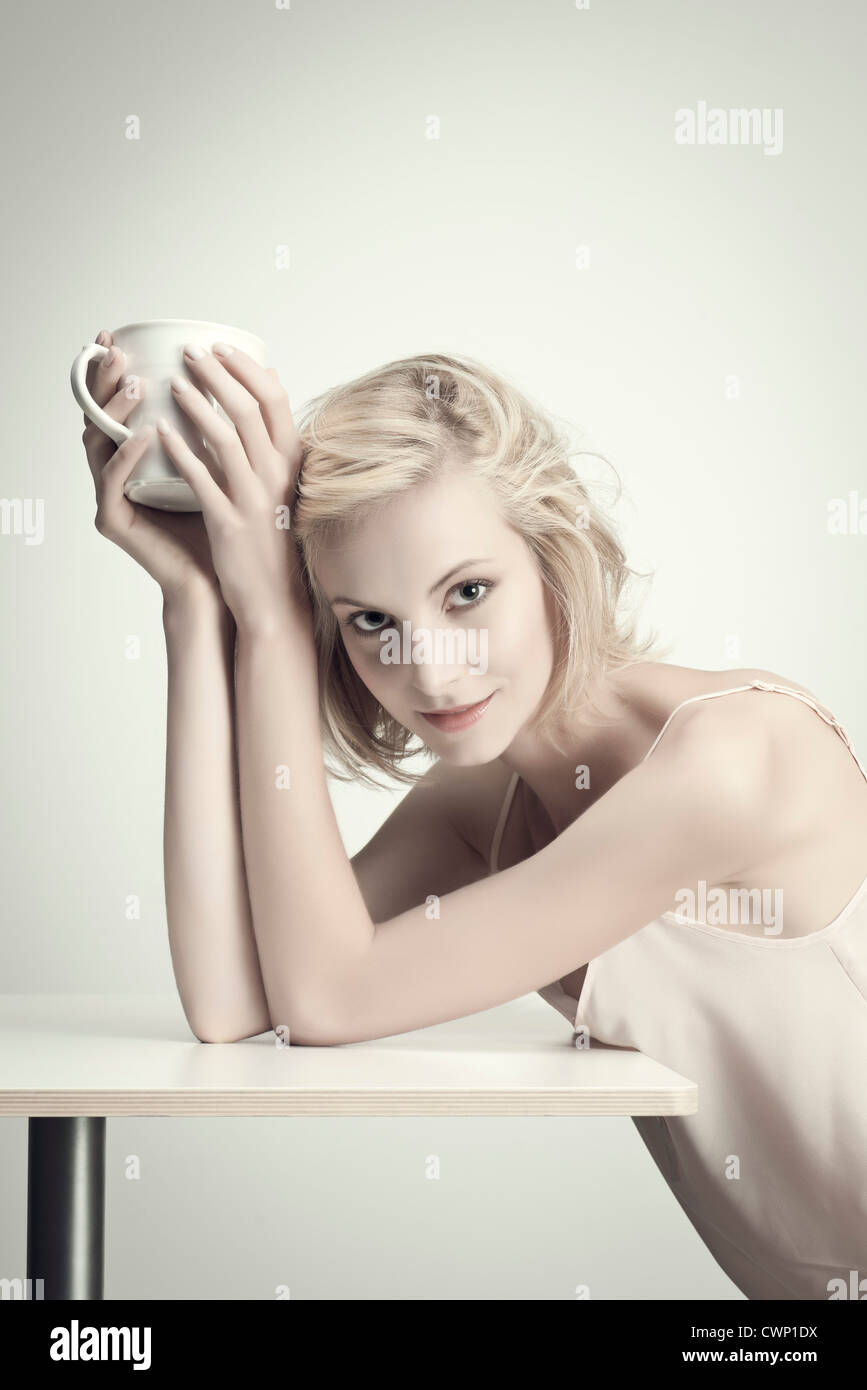 Young woman holding coffee cup at table, portrait Stock Photo