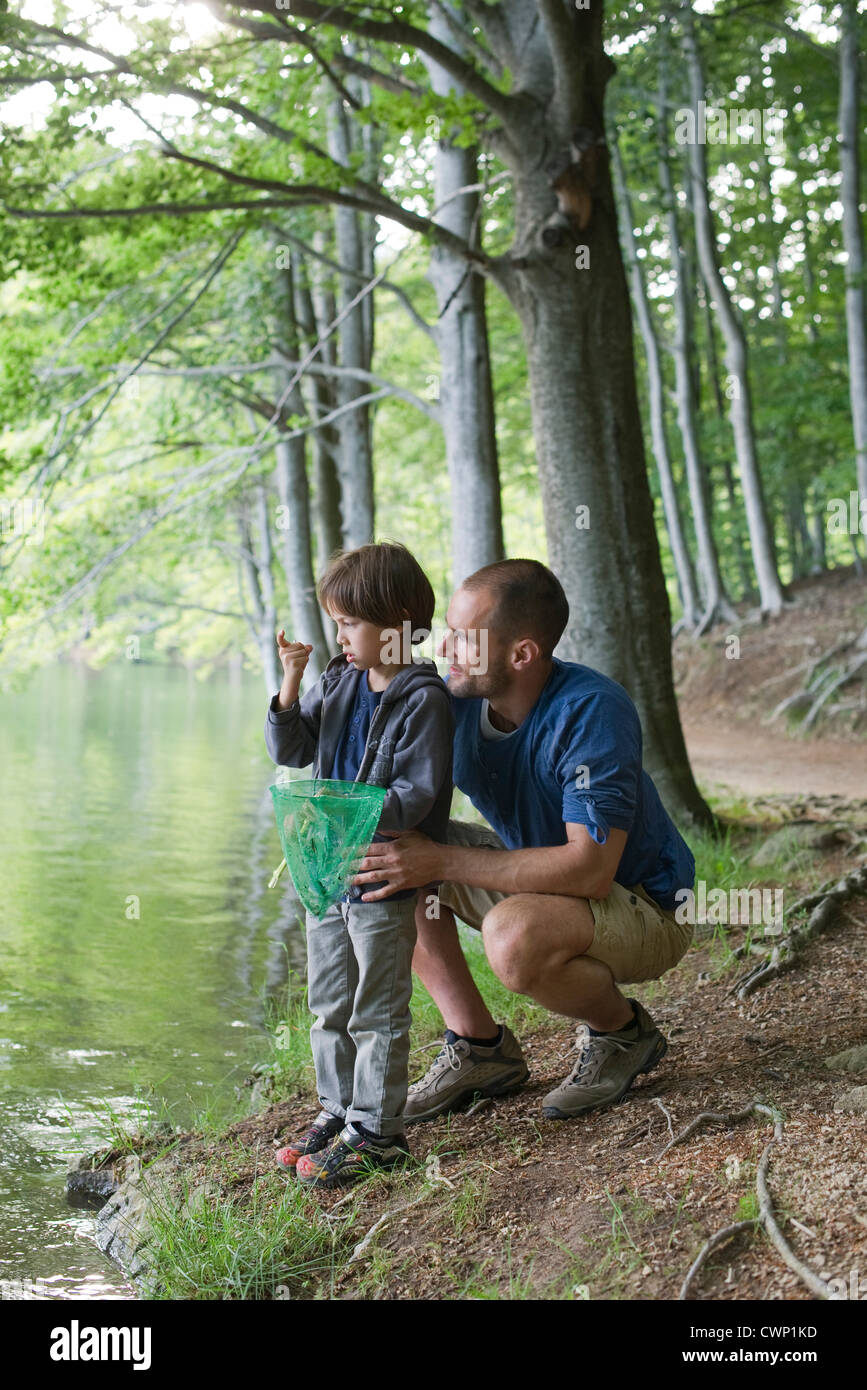 Father and son fishing, boy staring at tiny fish in hand Stock Photo