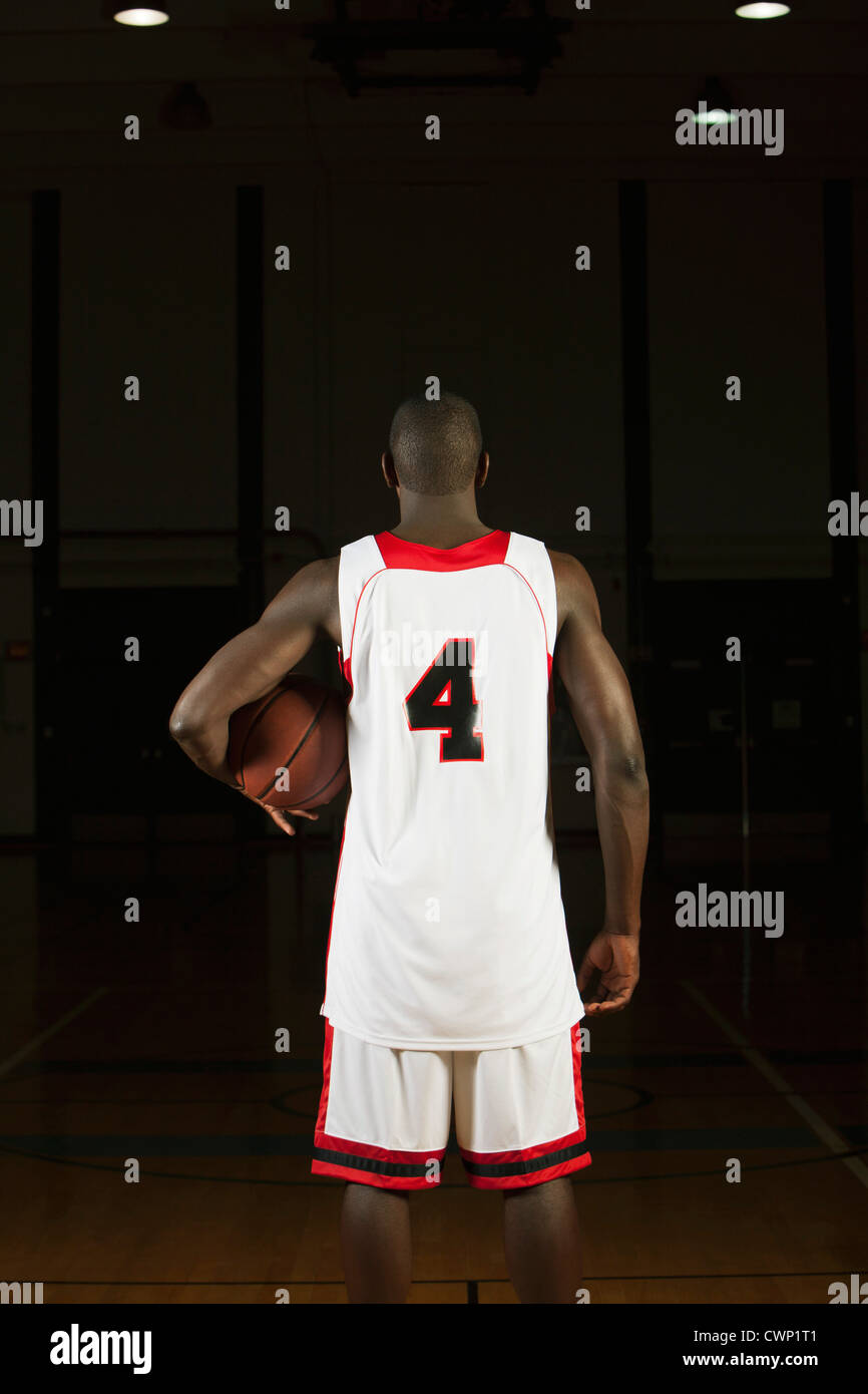 Basketball player holding basketball, rear view Stock Photo