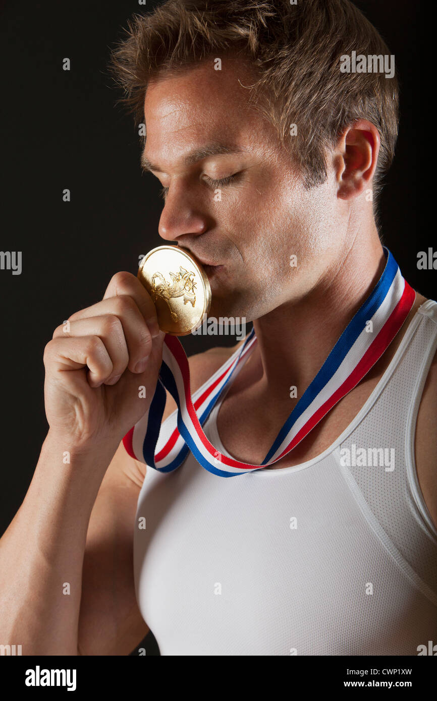 Male gymnast kissing gold medal, portrait Stock Photo