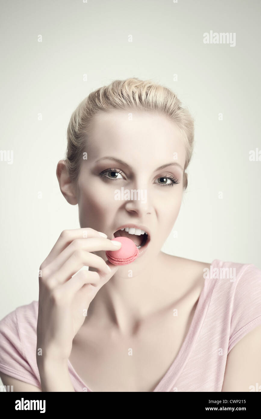 Young woman eating macaroon, portrait Stock Photo