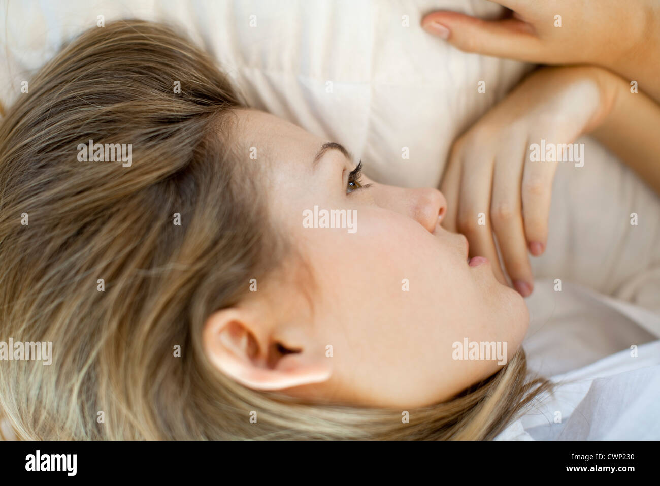 Woman lying down, looking away in thought Stock Photo
