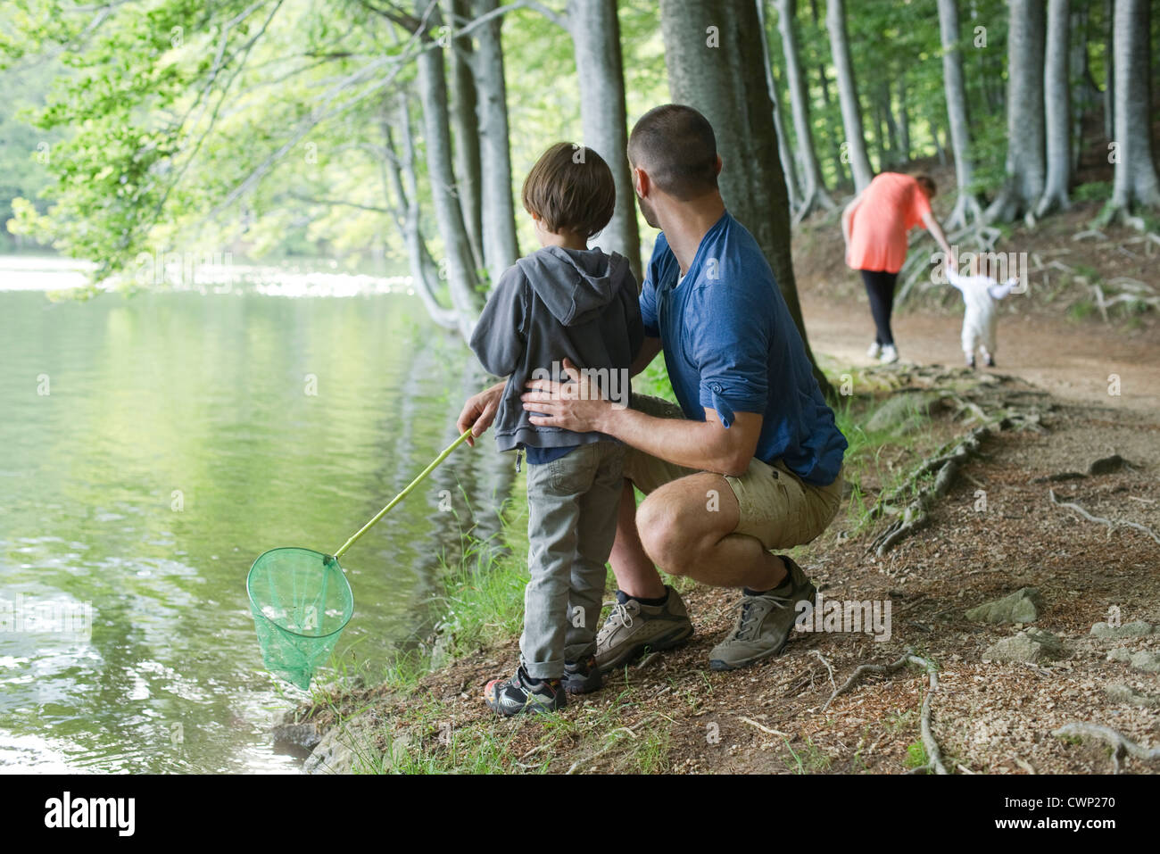 Father and son fishing in woods, both looking away Stock Photo