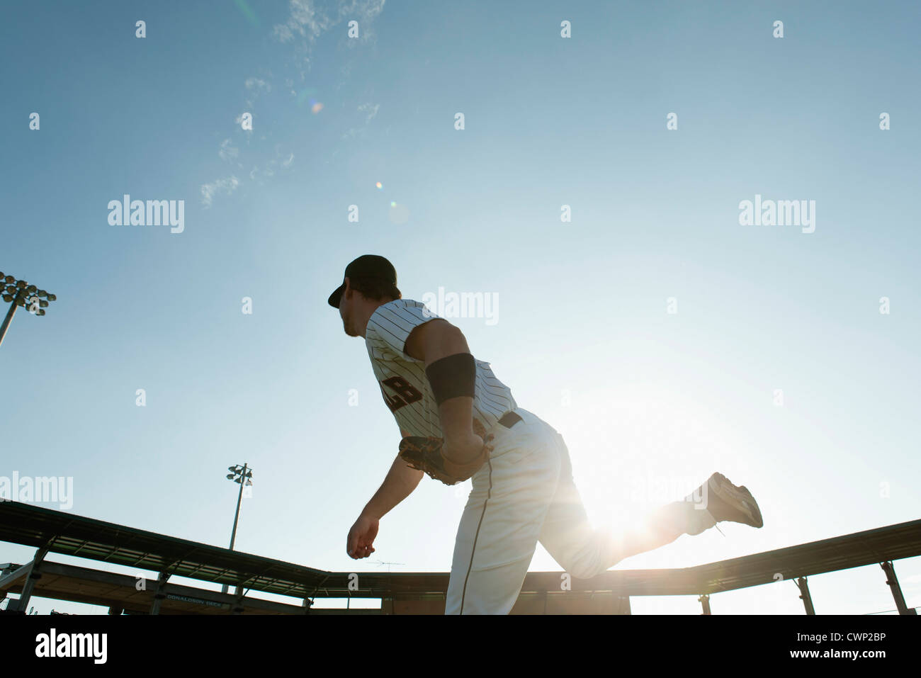 Baseball pitcher throwing pitch, backlit Stock Photo