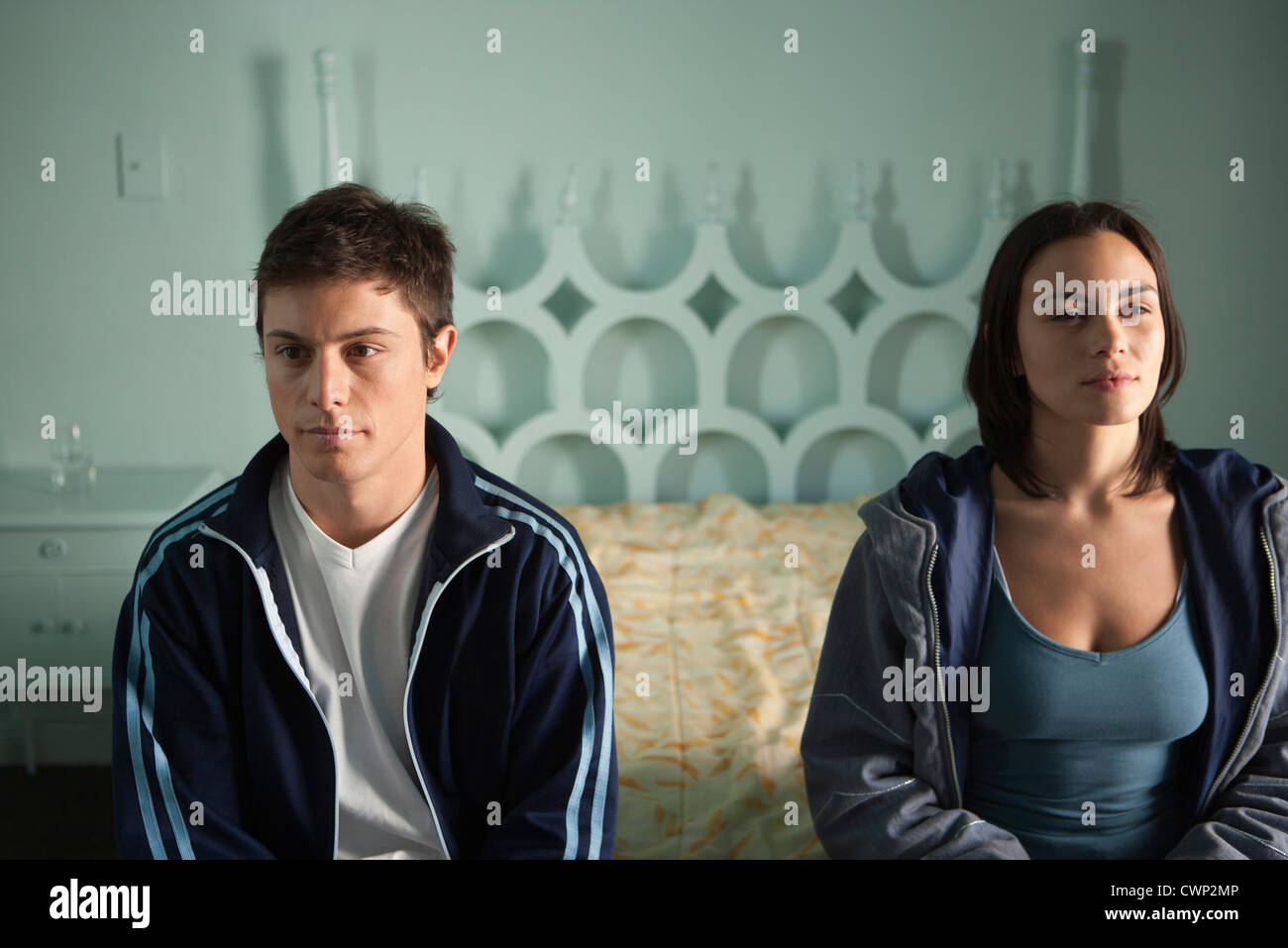 Couple sitting on bed, both looking away in thought Stock Photo