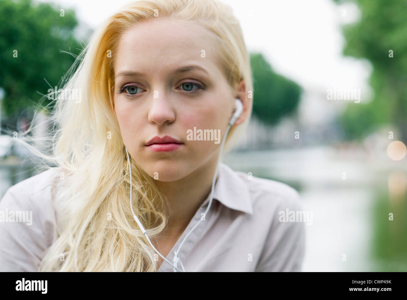 Young woman listening to earphones, looking away in thought Stock Photo