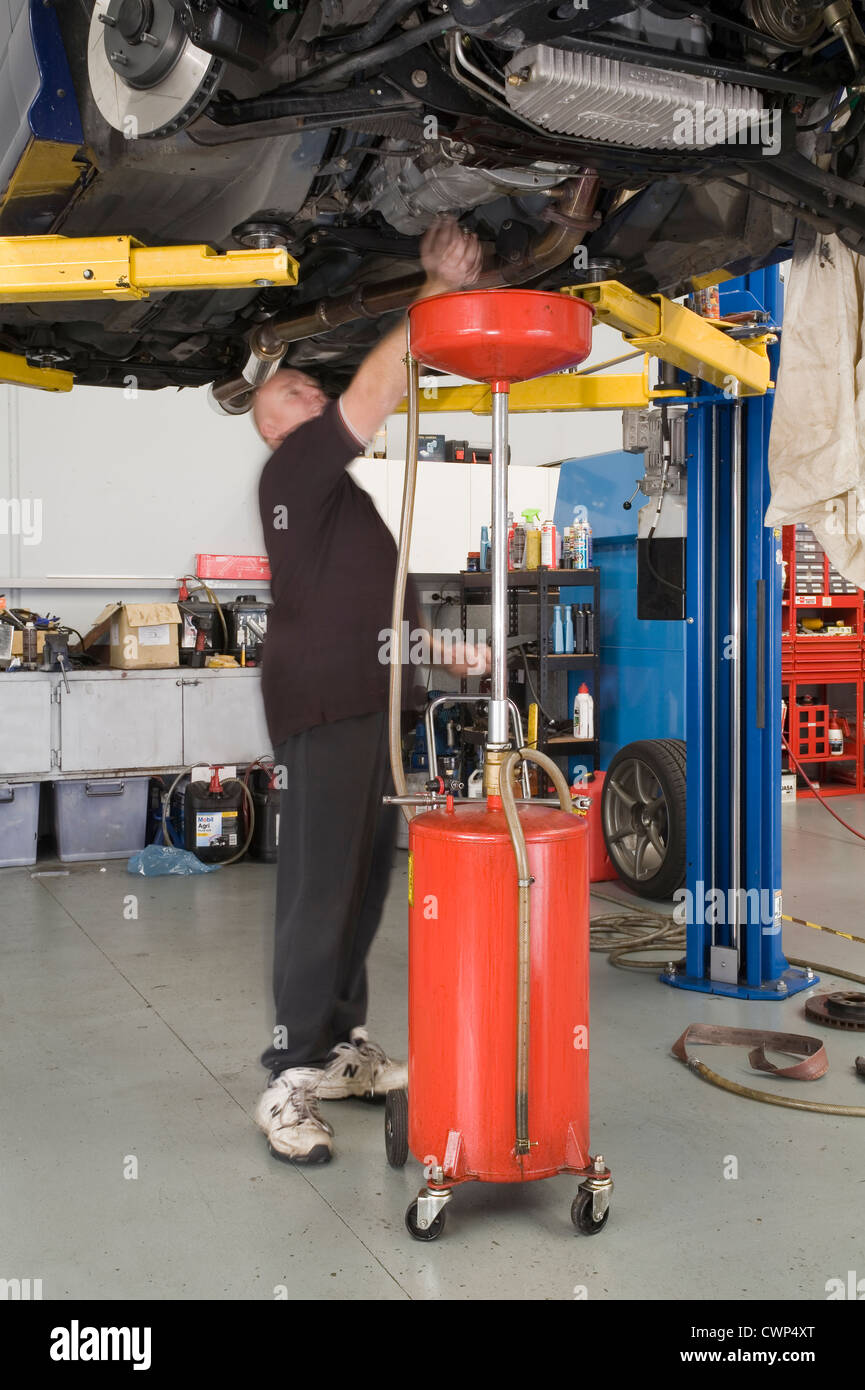 Car mechanic working in a garage changing the oil in a gearbox