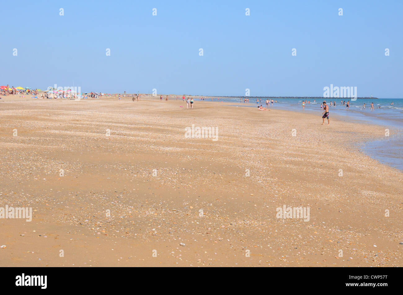 Wide expanse of golden sandy beach, holidaymakers in distance, blue sky, hot midday sun, Costa de la Luz. Stock Photo