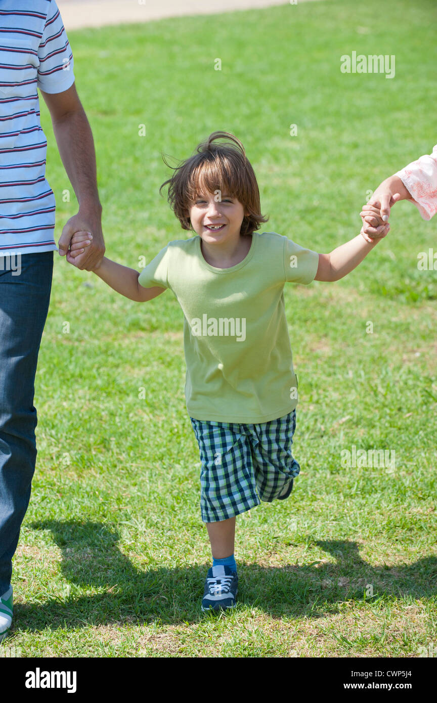 Boy walking hand in hand with parents outdoors, cropped Stock Photo