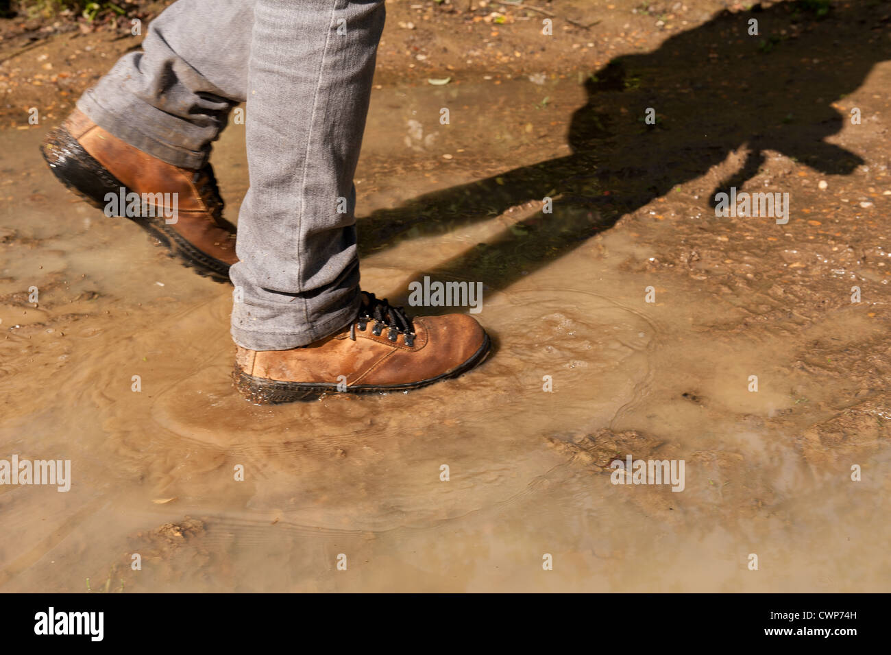 Rambling splashing in a puddle walking along river footpath just after raining has stopped and sunshine comes out between clouds Stock Photo