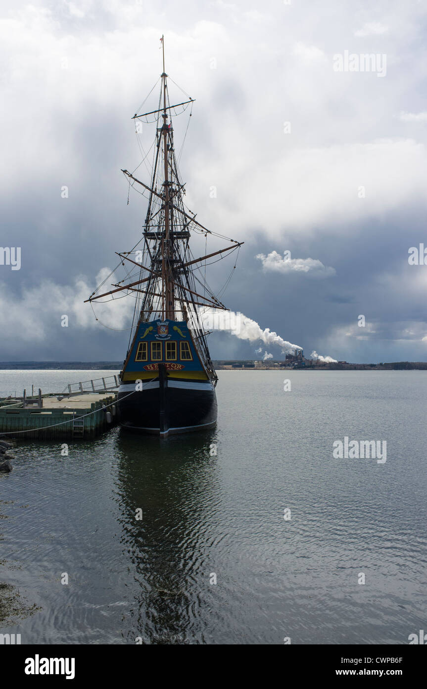 Pollution is emitted from a pulp mill across the bay from where a tall ship is docked. Stock Photo