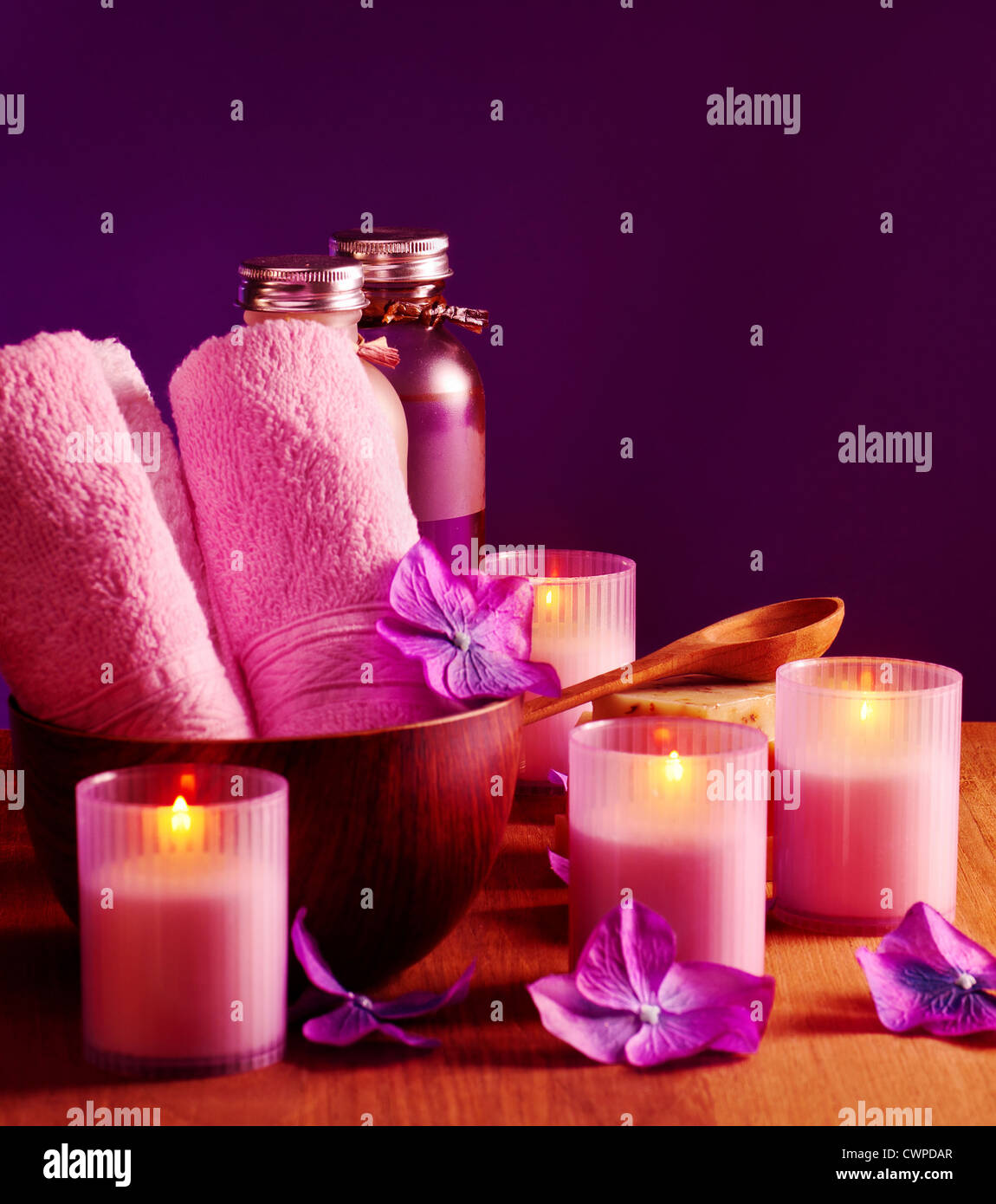Photo of spa still life on purple background, picture of pink bath candles  and bottles with massage oil, image of soft towel Stock Photo - Alamy