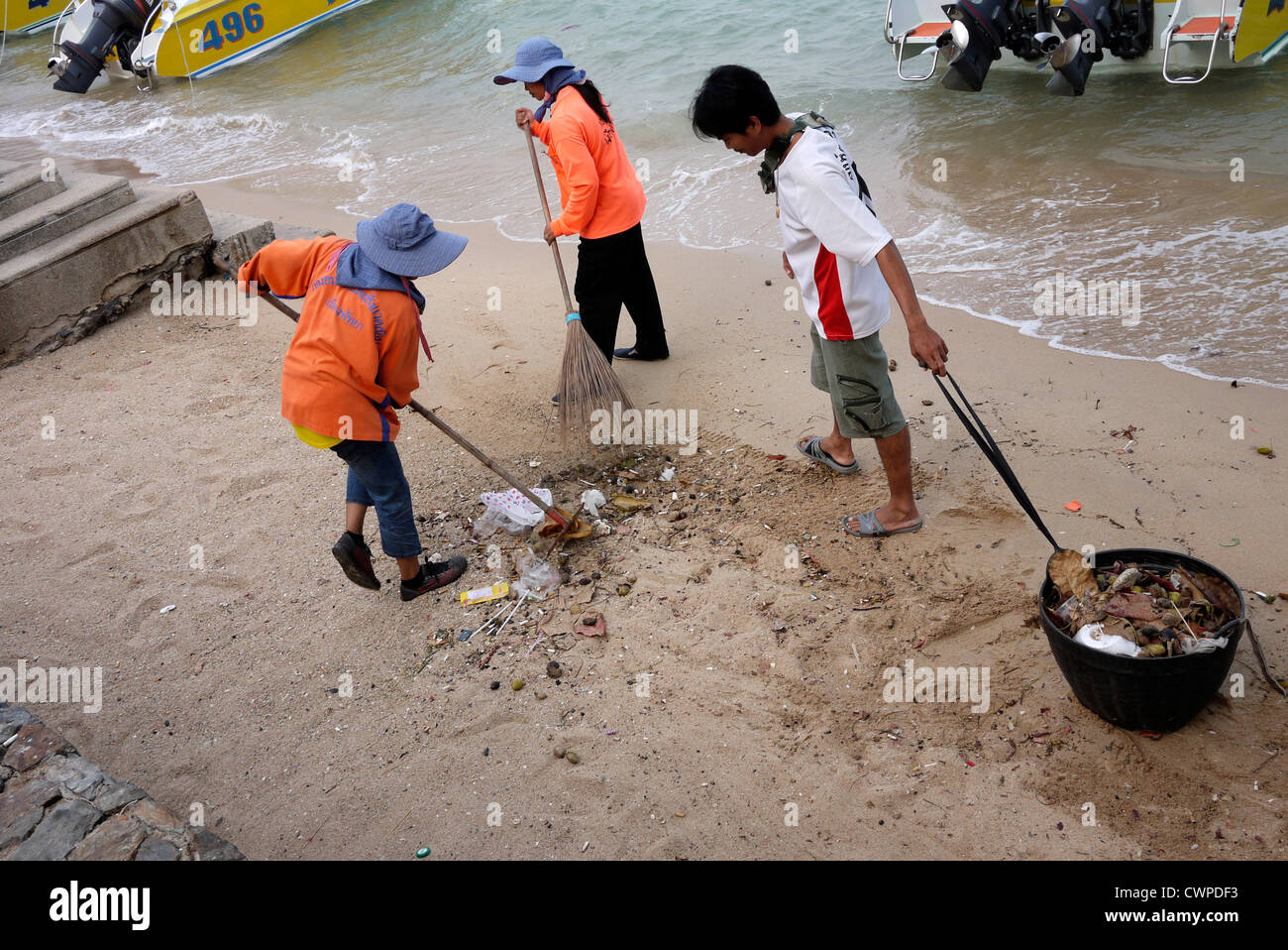 Beach cleaners sweep and clear rubbish from the beach in Pattaya Thailand Stock Photo