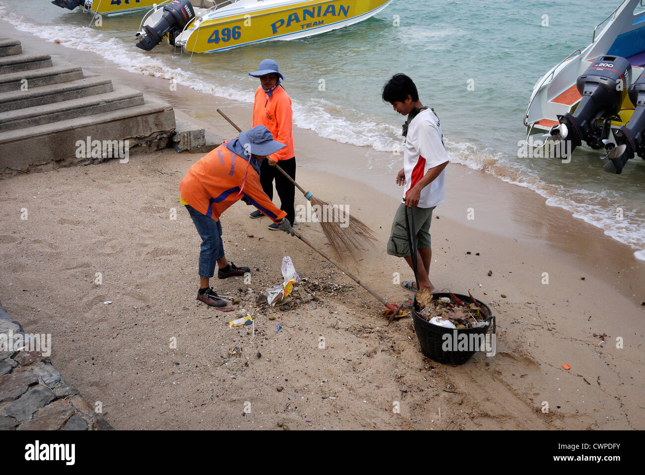 Beach cleaners sweep and clear rubbish from the beach in Pattaya Thailand Stock Photo