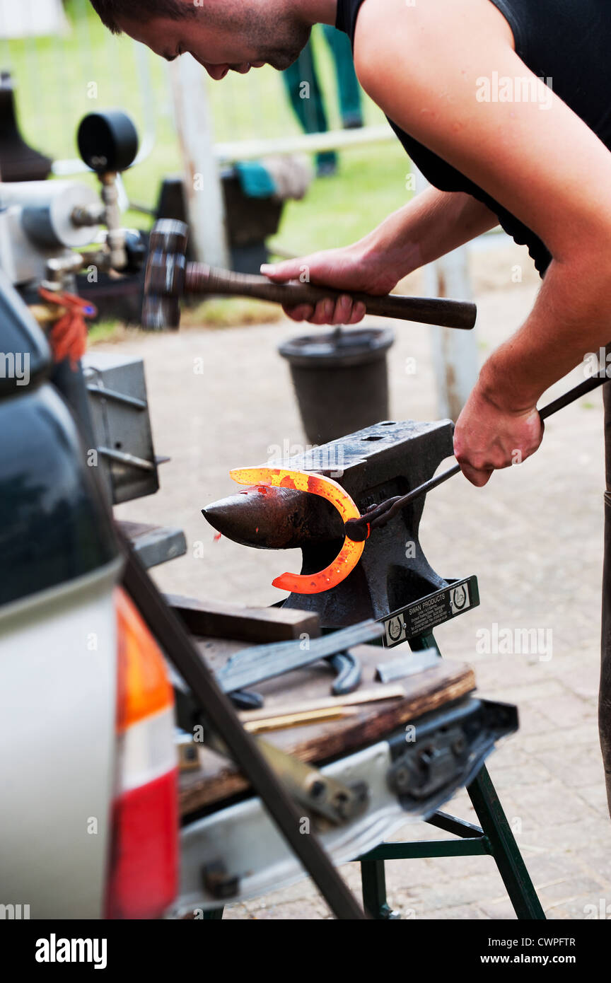 A farrier shaping a horseshoe Stock Photo