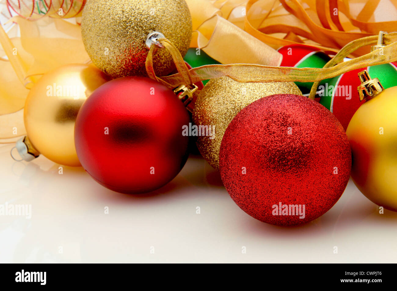 Closeup of Christmas tree ornaments on a white surface with reflections. Stock Photo