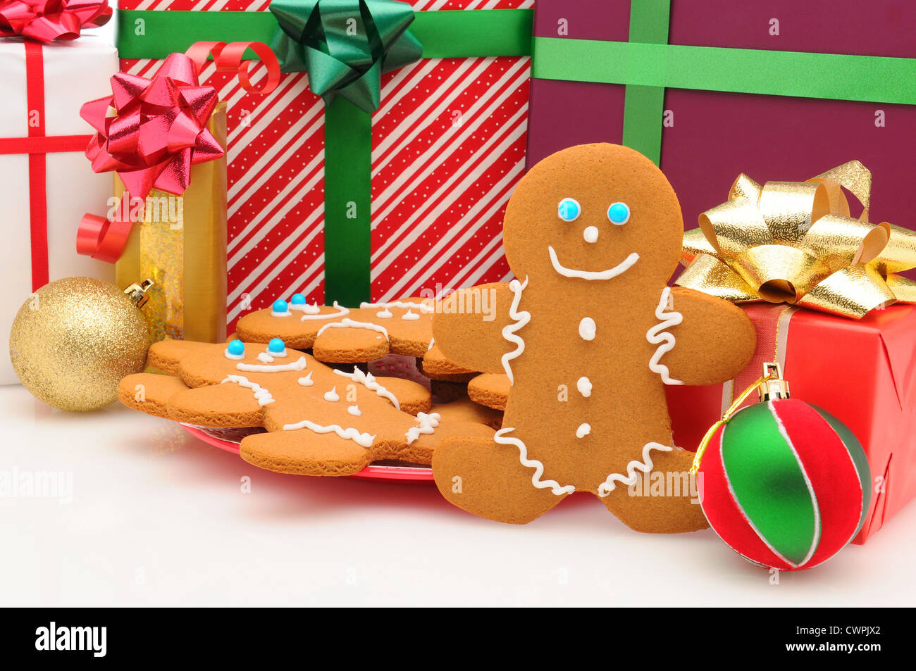 A plate of Ginger Bread Man cookies in front of Christmas presents. Horizontal format. Stock Photo