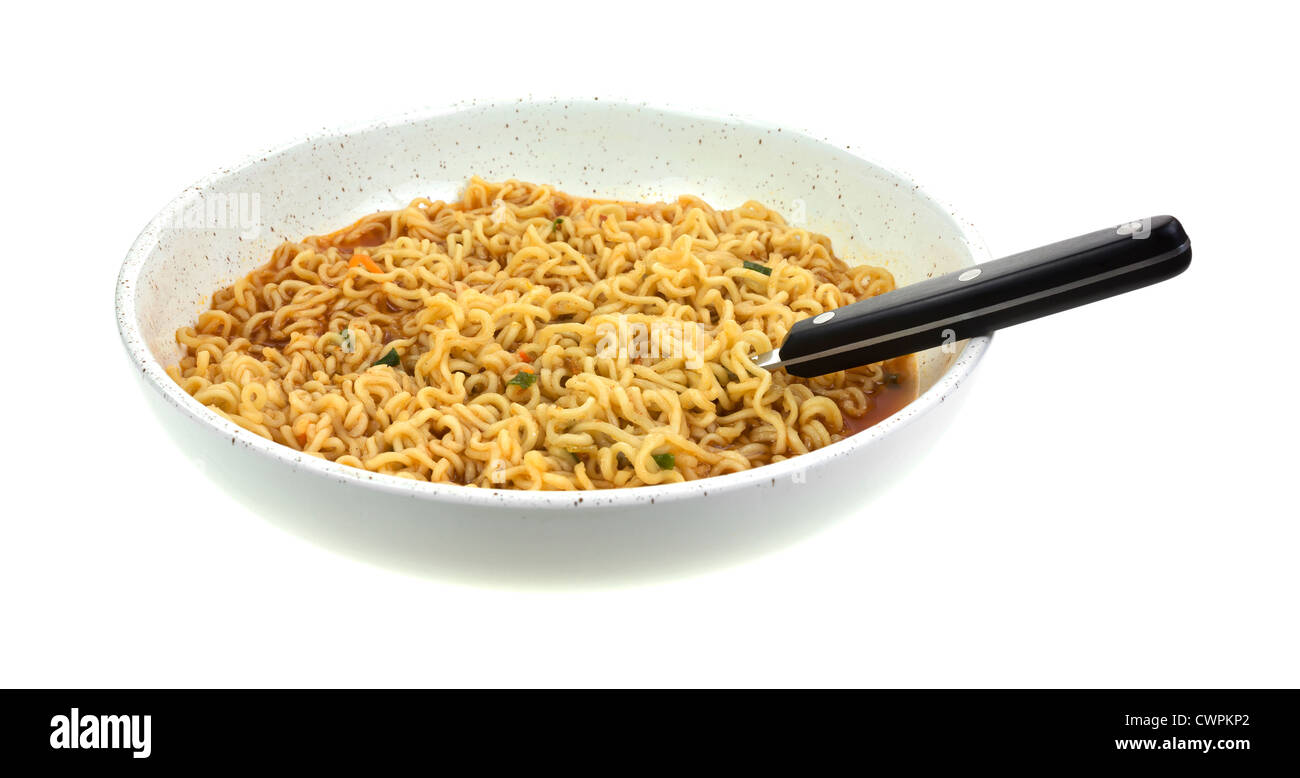 Side view of a shallow bowl of noodle soup with black handled spoon on a white background. Stock Photo