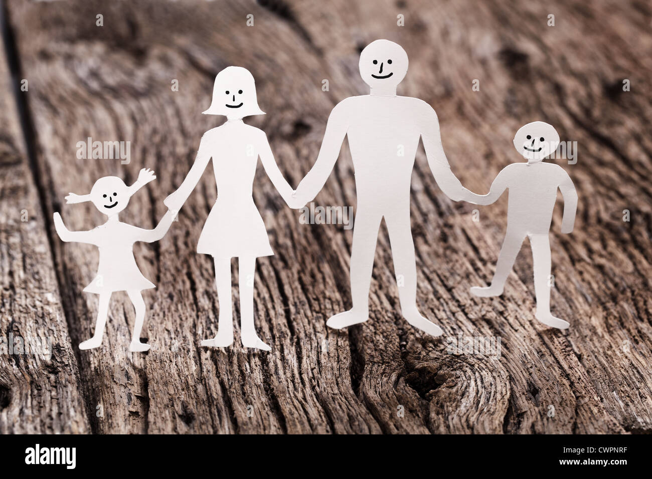 Cardboard figures of the family on a wooden table. The symbol of unity and happiness. Stock Photo
